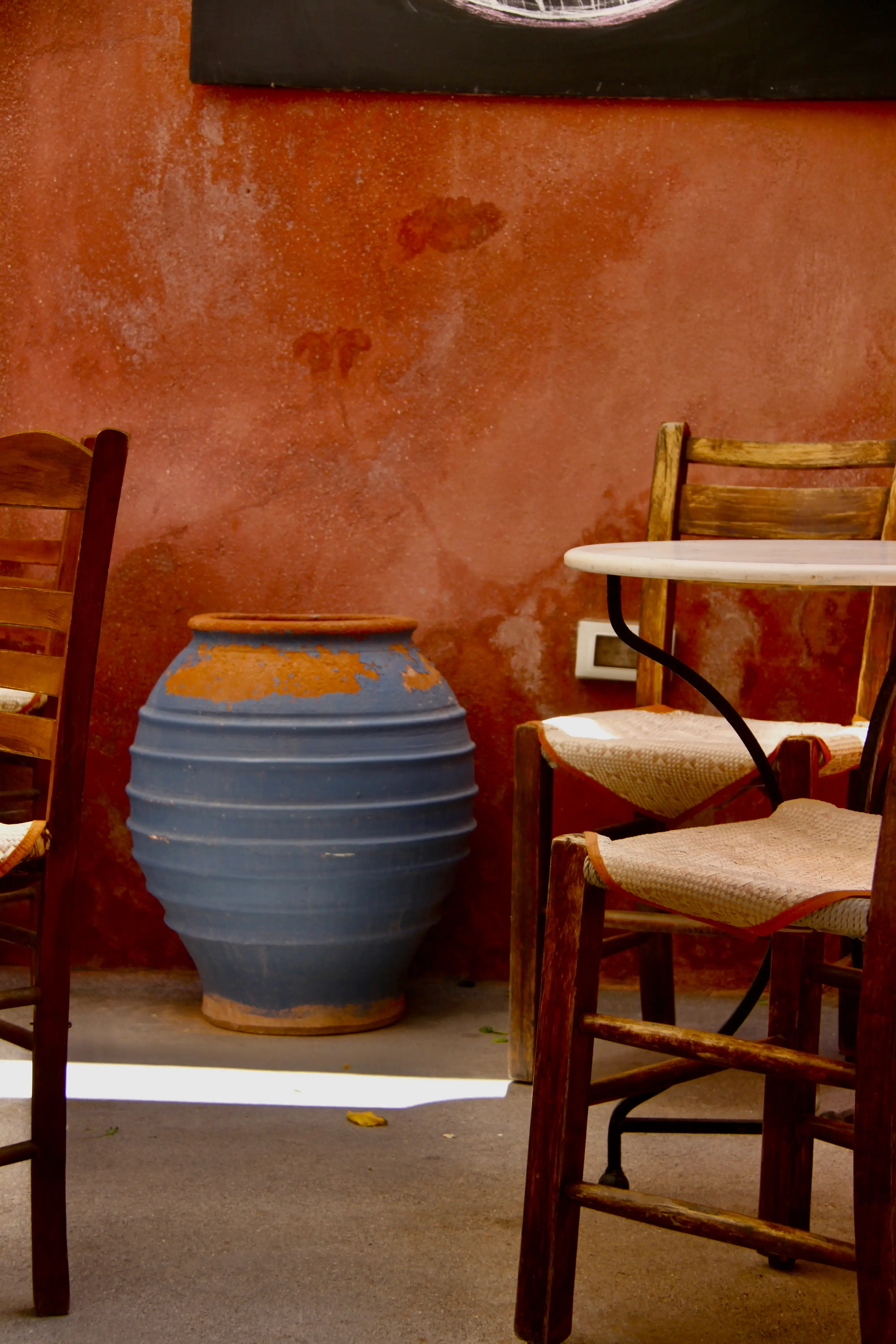 Blue jar and worn rush chairs against rose plaster